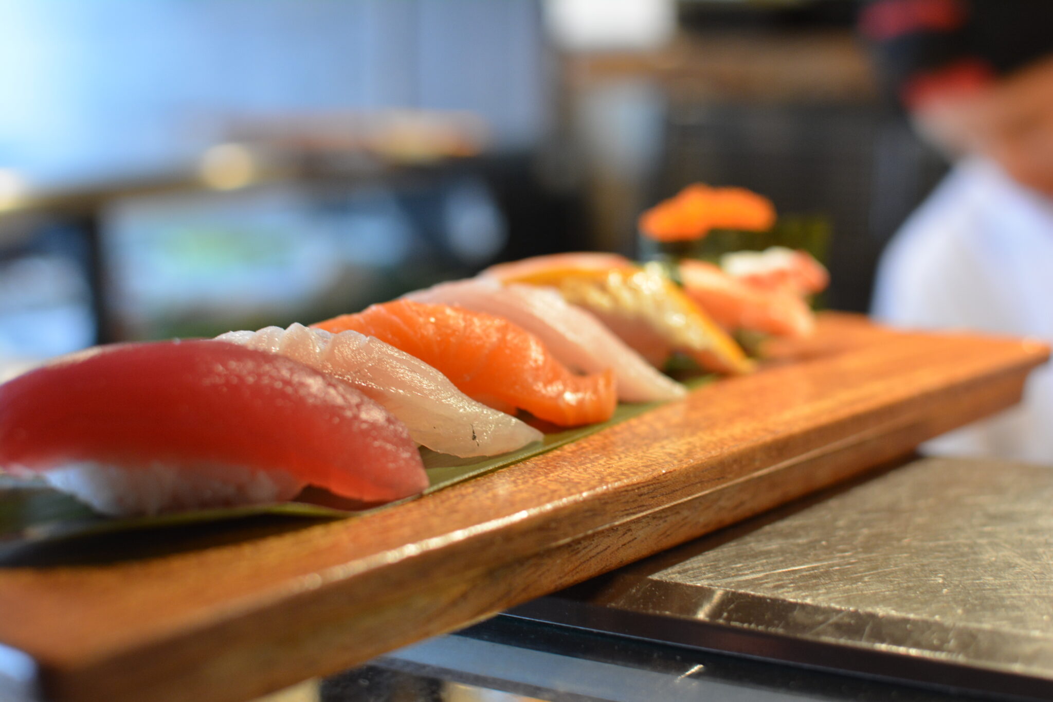 Assorted nigiri sushi lined up on a wooden board at a Bay Area sushi restaurant